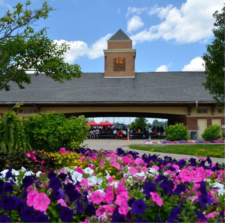 Flower garden in front of a pavilion whose tower sign reads Fallview